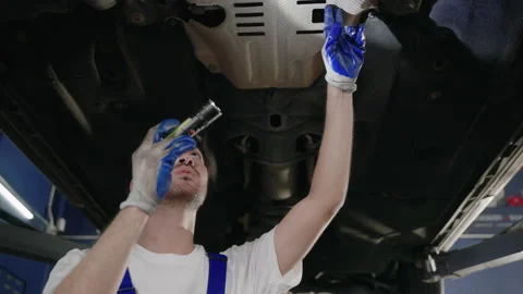 Auto mechanic is walking to check the condition of the car that is on the hoist Stock-Footage 205745348