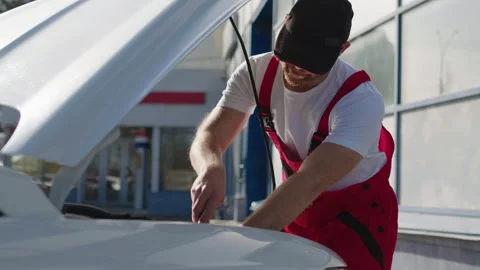 Auto mechanic in work clothes diligently repairs the broken down car brought to Stock Footage 282742975
