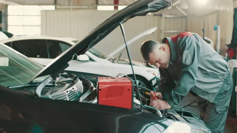 Auto mechanic working on car diagnostic in a repair shop. Electrician working on Stock Footage 180855704
