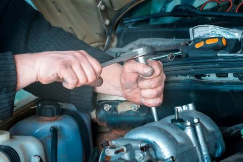 Auto mechanic working on car engine in mechanics garage. Repair service. Clos Stock Photos