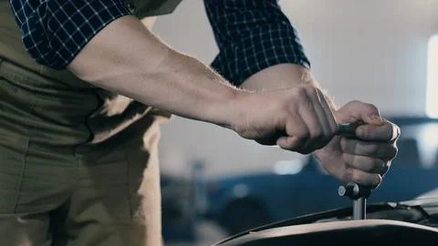 An auto mechanic is working on a car engine in a car workshop. Close-up ratchet Stock Photos