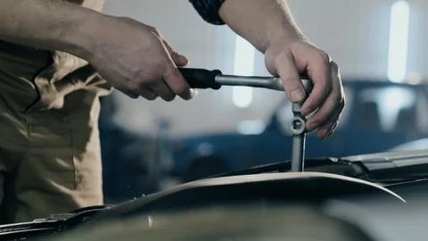 An auto mechanic is working on a car engine in a car workshop. Close-up ratchet Stock Photos