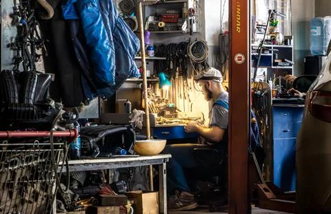 Auto mechanic working at cluttered bench in busy service center workshop Stock Photos