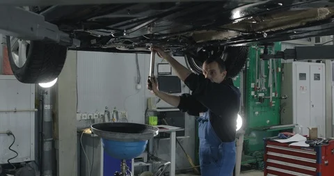 Auto Mechanic Working Under The Car In Dealer's Garage. Video stock 124968153