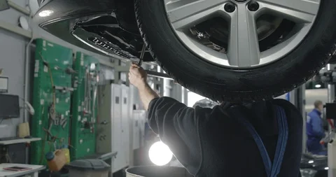 Auto Mechanic Working Under The Car In Dealer's Garage. Video stock 124968306
