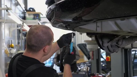 An auto mechanic working under the car on a car lift in the garage. Stock Footage 300833098