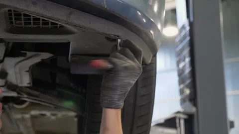 An auto mechanic working under the car on a car lift in the garage. Car service. Stock Footage 337221120