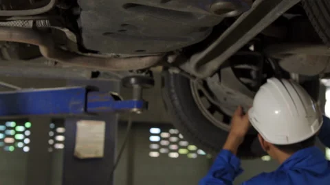Auto mechanic working underneath car lifting machine at the garage. Видео 145346787