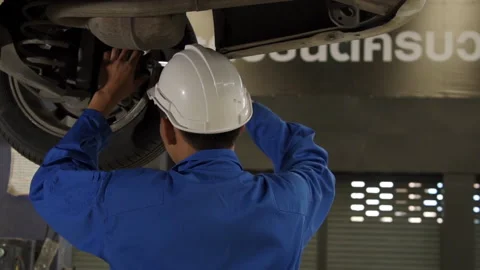Auto mechanic working underneath car lifting machine at the garage. Stock Footage 145346854