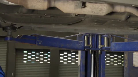 Auto mechanic working underneath car lifting machine at the garage. Stock Footage 145347240