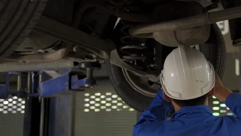 Auto mechanic working underneath car lifting machine at the garage. Stock Footage 145347278