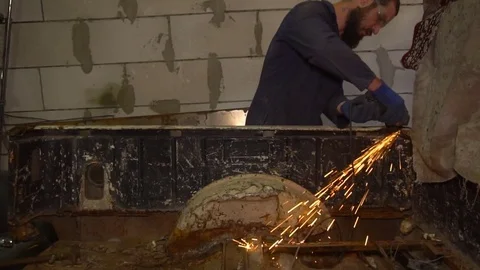 Auto mechanic works with a grinder tool cutting a rusty metal Stock Footage 80928807