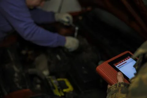 Auto mechanics collaborating in a garage, using electronic diagnostic software Stock Photos