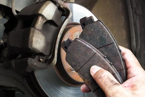 Auto mechanics replace worn brake pads to maintain a car braking system Foto stock