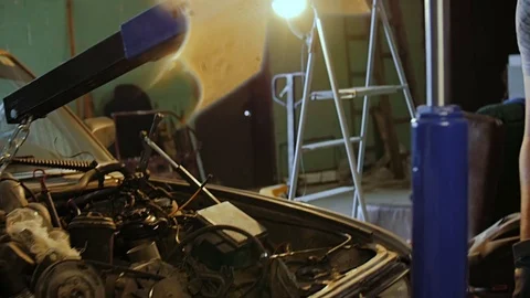 Auto mechanics use a mini crane to pull the motor out of the car's hood. Stock Footage 77175427