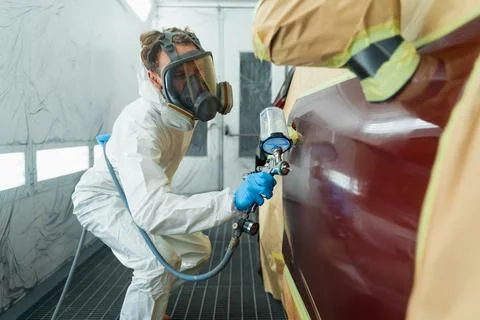 Auto painter in a protective suit and mask sprays a degreaser 스톡 사진