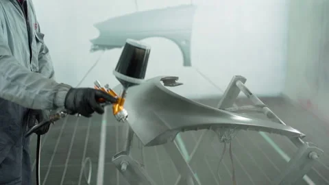 Auto painter spraying black paint on the wing of the car in special garage box Stock Footage 153489372