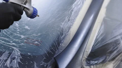 Auto painter spraying black paint on the parts of the car in special booth Stock Footage 194801064