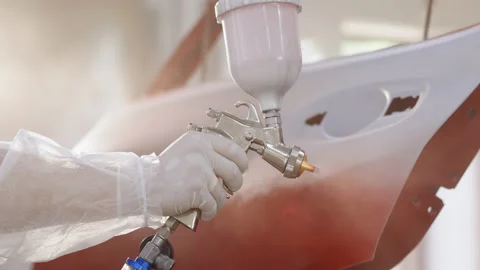 Auto painter spraying red paint on car door in special booth, slow motion Stock Footage 194558824