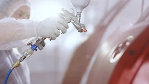 Auto painter spraying red paint on the rear door of the car in special booth Stock Footage 194563406