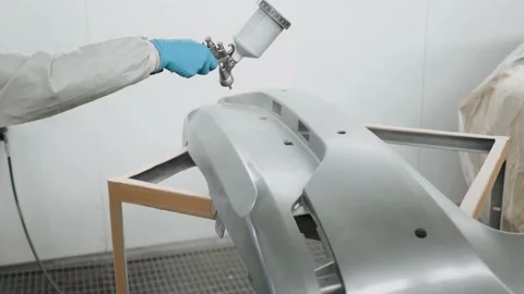 Auto painter spraying silver paint on car front bumper in special booth. Stock Footage 136300355