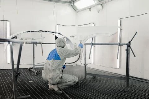 Auto painter spraying silver paint on the rear bumper of the car in special Stock Photos