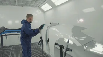 Auto painter spraying white paint on car spare fender in special booth Stock Footage 86089699