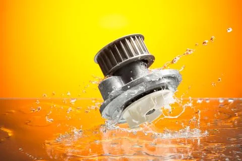 Auto parts, engine cooling pump in water splash on orange background Stock Photos