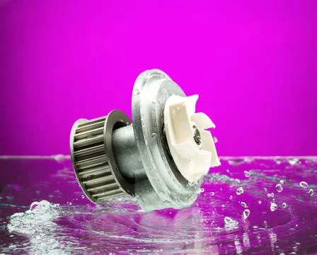 Auto parts, engine cooling pump in spurts of water on purple background. Stock Photos