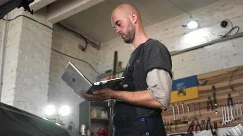 Auto repairman diagnoses a car using a computer. car workshop Stock Footage 204082672