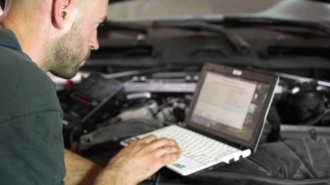 Auto repairman diagnoses a car using a computer. car workshop. close-up 動画素材 204082810