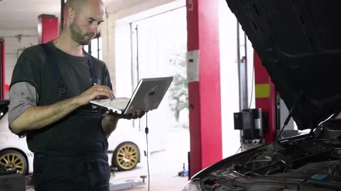Auto repairman diagnoses a car using a computer. car workshop 動画素材 204082911