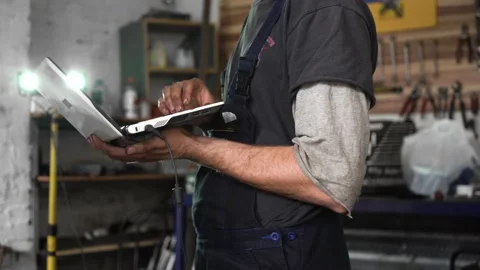 Auto repairman diagnoses a car using a computer. car workshop. close-up Stock Footage 204878690