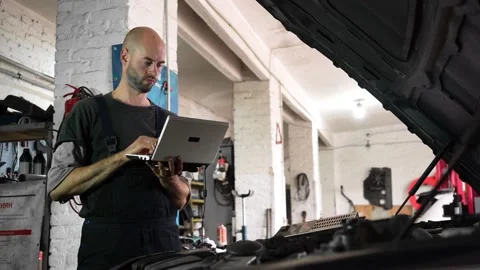 Auto repairman diagnoses a car using a computer. car workshop Vídeos de archivo 204878717