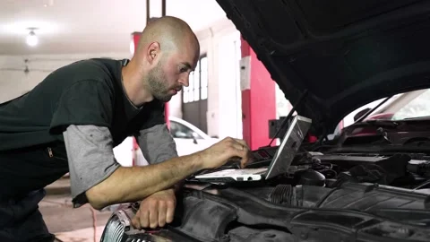 Auto repairman diagnoses a car using a computer. car workshop Stock Footage 204878729