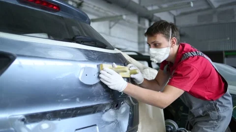 Auto repairman makes surface preparation of automobile body Stock Footage 152875476