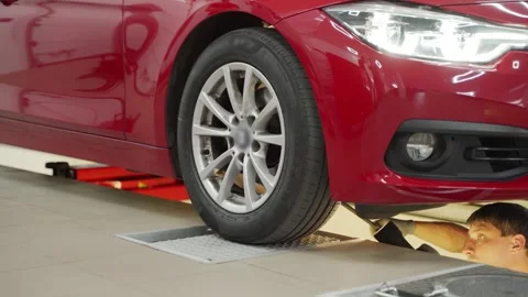 Auto service worker performs hydraulic play detector check on car, assessing Stock Footage 272309491