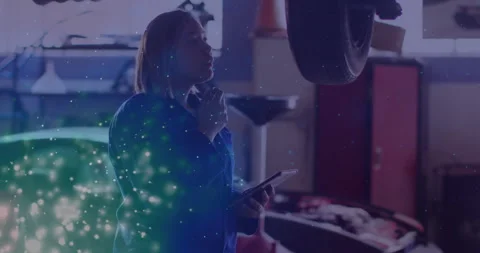 Auto technician inspecting tire, with data graphs floating on tablet screen for Stock Footage 308101193