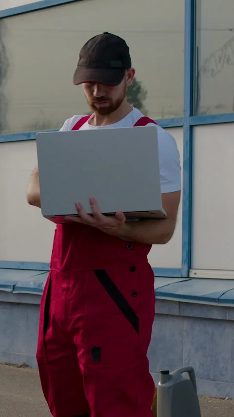 Auto technician in red overalls diagnosing car air conditioning system with Stock Footage 320393975