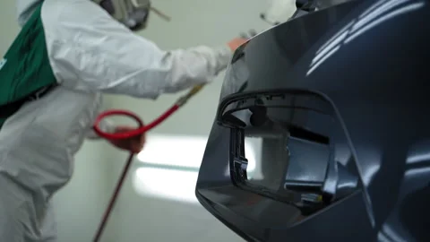 Auto technician spray gloss lacquer on car bumper inside clean, ventilated paint Stock-Footage 321664519