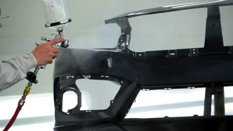 Auto technician spraying gloss lacquer on car bumper inside clean, ventilated 库存影片 322088018