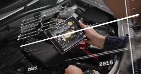 Auto technician wearing dark jacket analyzing engine in garage with tablet Foto stock