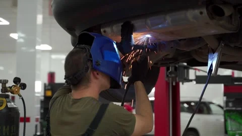 Auto technician welds exhaust flex pipe on vehicle. Mechanic repairs car Stock Footage 269030032