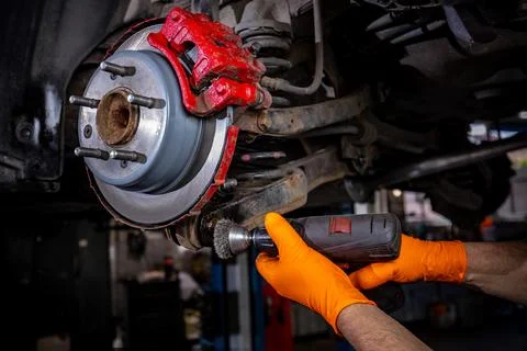 Auto Worker Cleaning Rust from Wheel Mount in Service Stock Photos