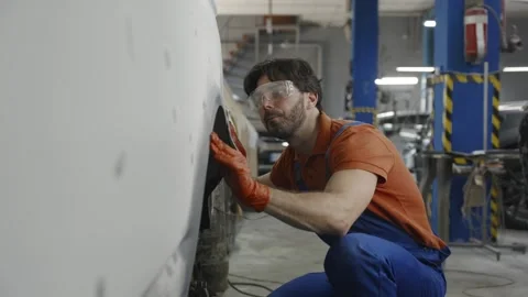 Auto worker sanding and prepping a car panel for painting in a garage workshop. Stock Footage 326249201