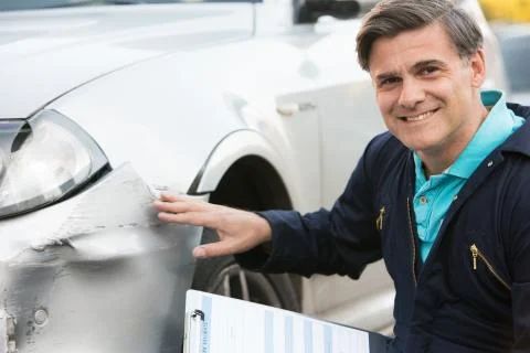 Auto Workshop Mechanic Inspecting Damage To Car And Filling In Repair Estimat Stock Photos