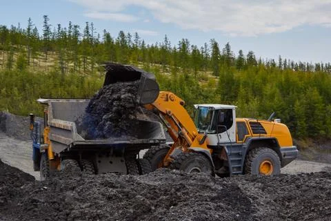 Autoloader loading gold sands onto a dump truck. Gold mining in Kolyma Photos