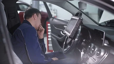 Automaster sitting in a car and thinking how to do chip tuning Stock Footage 75319685