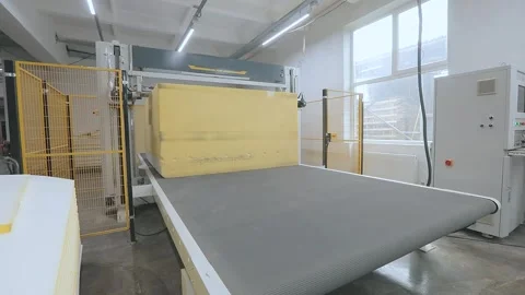 Automated CNC foam cutting machine processing a large block of polyurethane foam Video stock 347575871