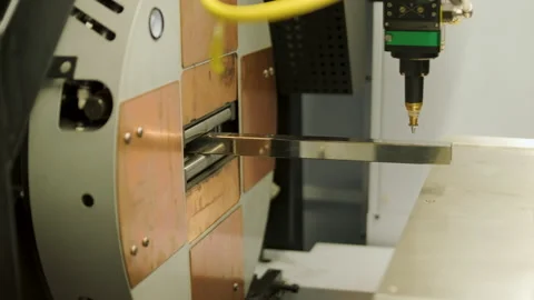 Automated CNC laser cutting machine processing a square metal pipe with bright Stock Footage 345892720